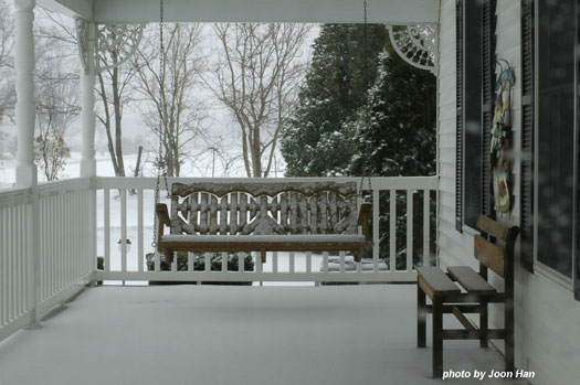 Lovely snowy scene of country style porch in the winter with porch swing