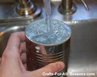 filling tin can with water to freeze to make luminaries