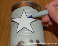 placing star stencil on tin can for luminaries