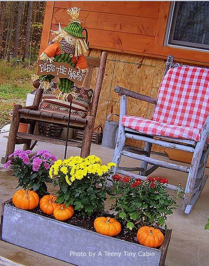 porch decorated for fall with pumpkins and mums