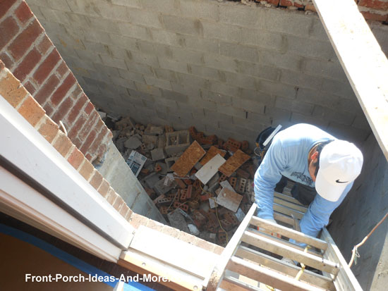 worker descending ladder into front porch cavity