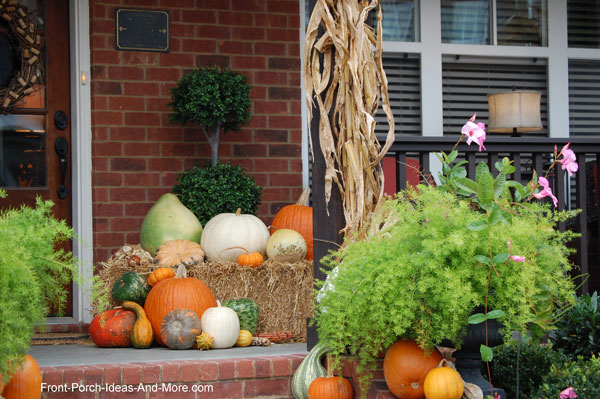 front door and porch decorated for Thanksgiving with pumpkins and corn stalks