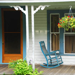 wooden screen door on front porch with rocking chairs