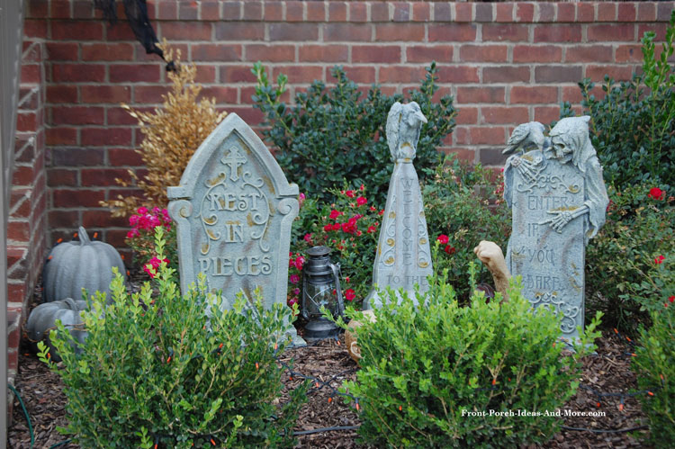 faux graveyard headstones placed amongst front porch landscaping