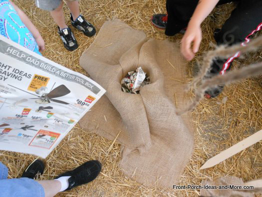 packing newspaper into bucket for scarecrows head