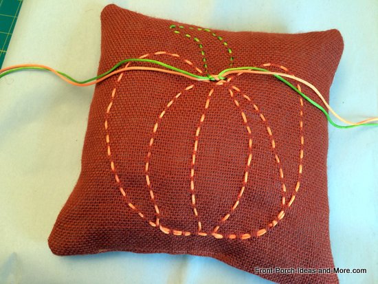A cute little burlap pillow decorated with a pumpkin motif - just ribbon weaved in the burlap