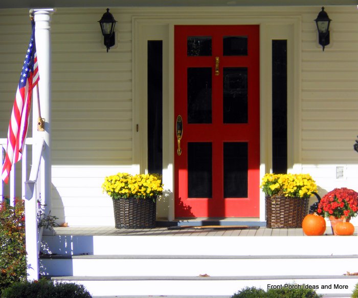 delightful fall front porch with red door and  mums
