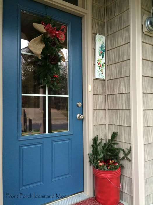 Christmas front door with red paint bucket filled with greenery