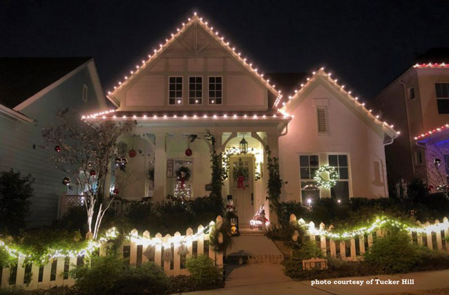 Christmas lights outlining home's roof line and on picket fence
