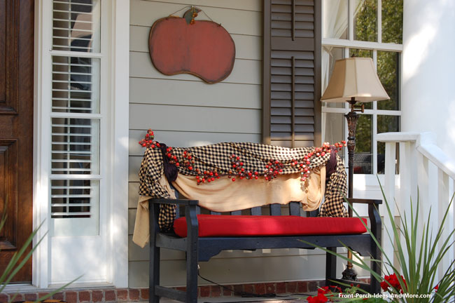 bench on front porch draped with autumn coverings