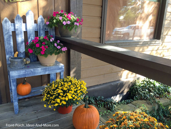 old chair, mums, and pumpkins for fall on front porch