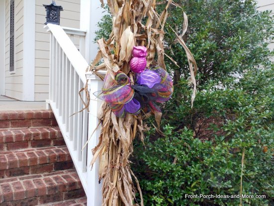 Cornstalks tied to porch step rails and decorate with colorful purple ribbons and cute owls