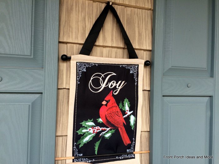 Joy winter wallhanging hangs between the shutters on our front porch
