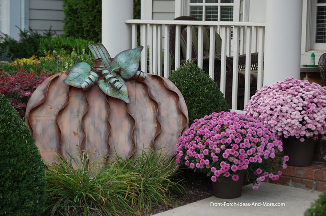 Large metal pumpkin in porch landscaping for fall