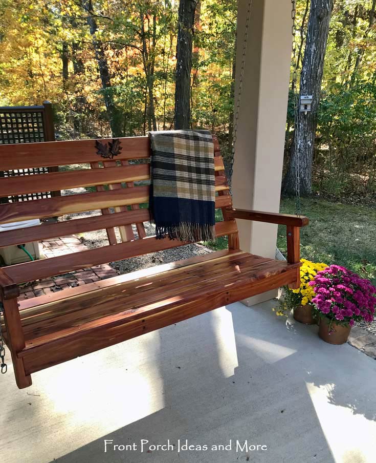 our cedar front porch swing with a plaid blanket