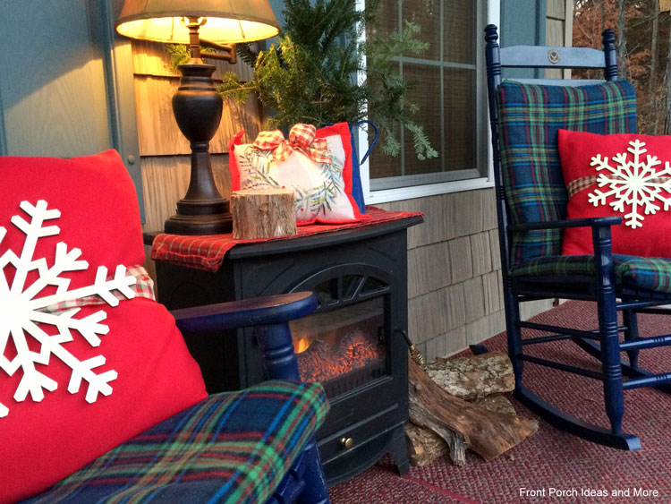our Christmas porch with plaid chair covers, stars on the pillows and a fireplace