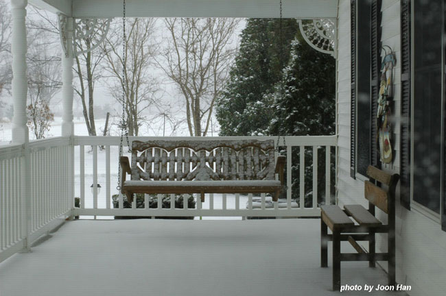 snow covered front porch and porch swing