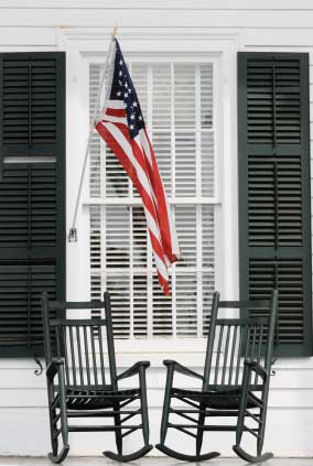 two black rocking chairs and flag on porch